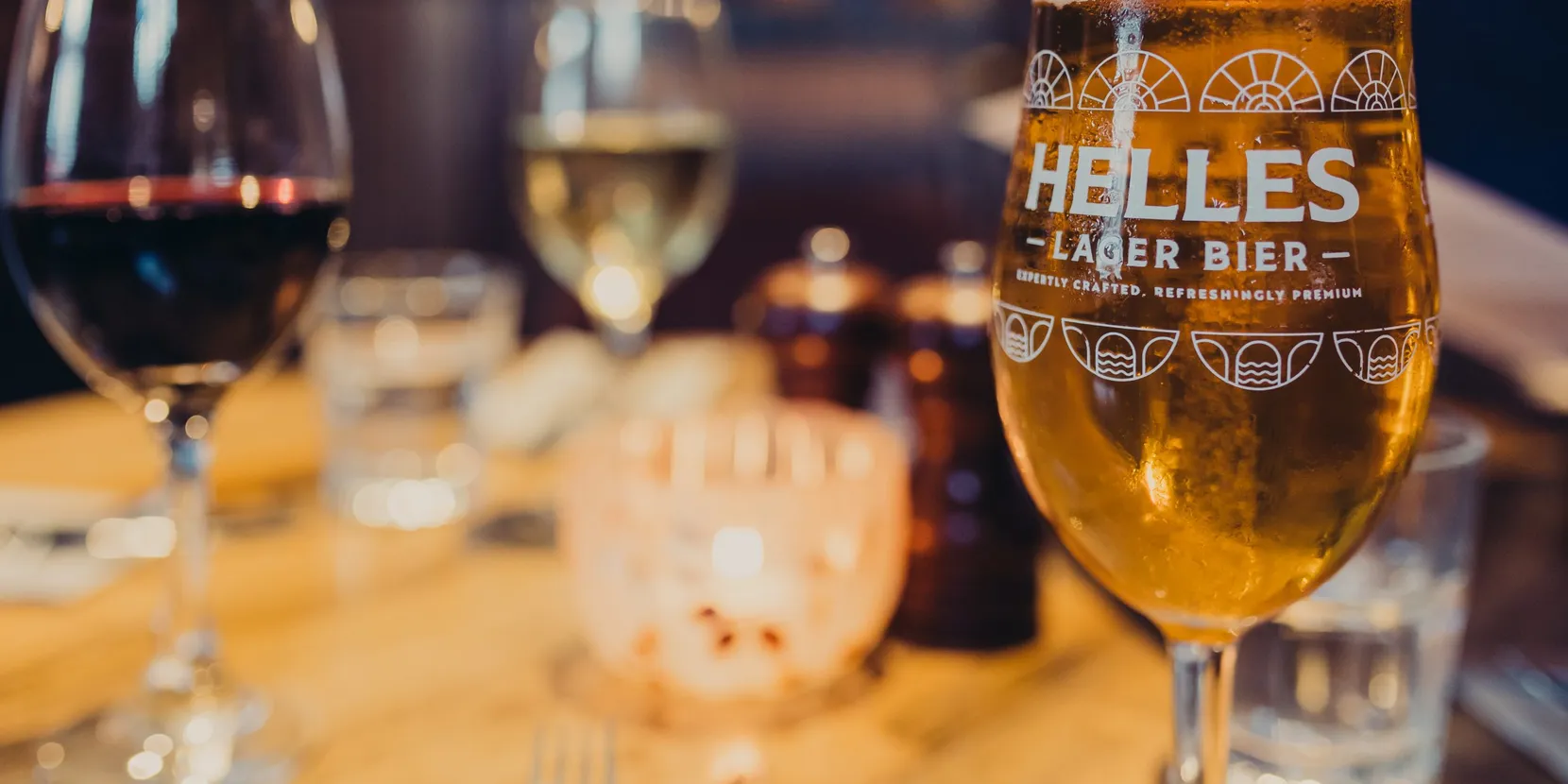 Several wine glasses filled with various drinks. One wine glass says 'Helles' on it.