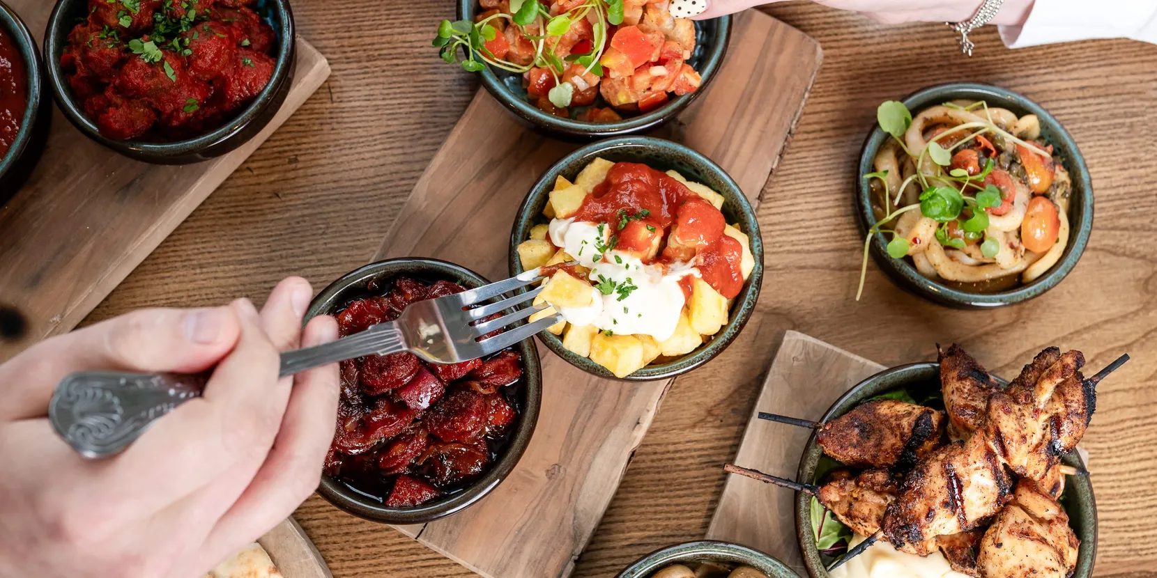 Various small dishes on a table with someone putting their fork into one