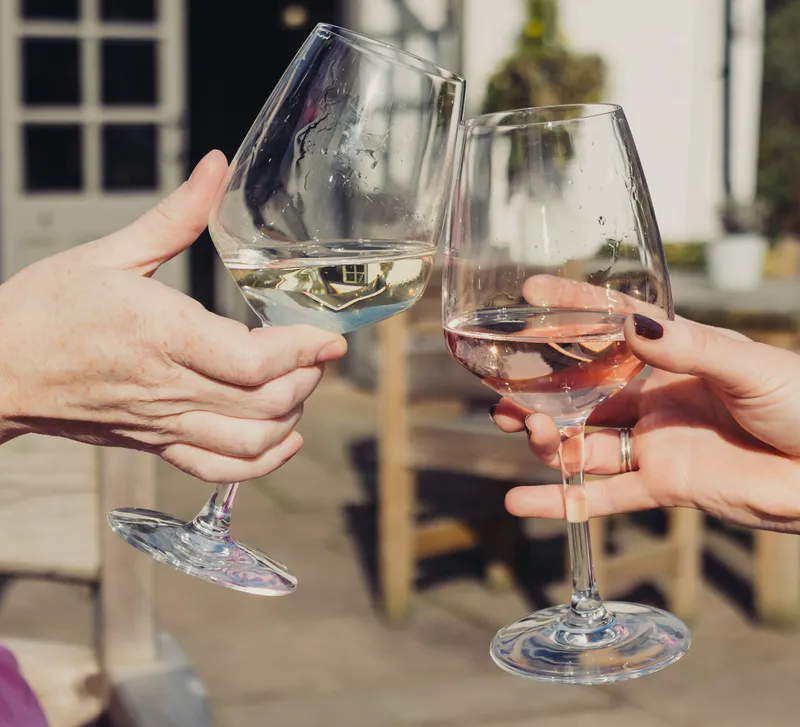 Two people clinking glasses with wine in them