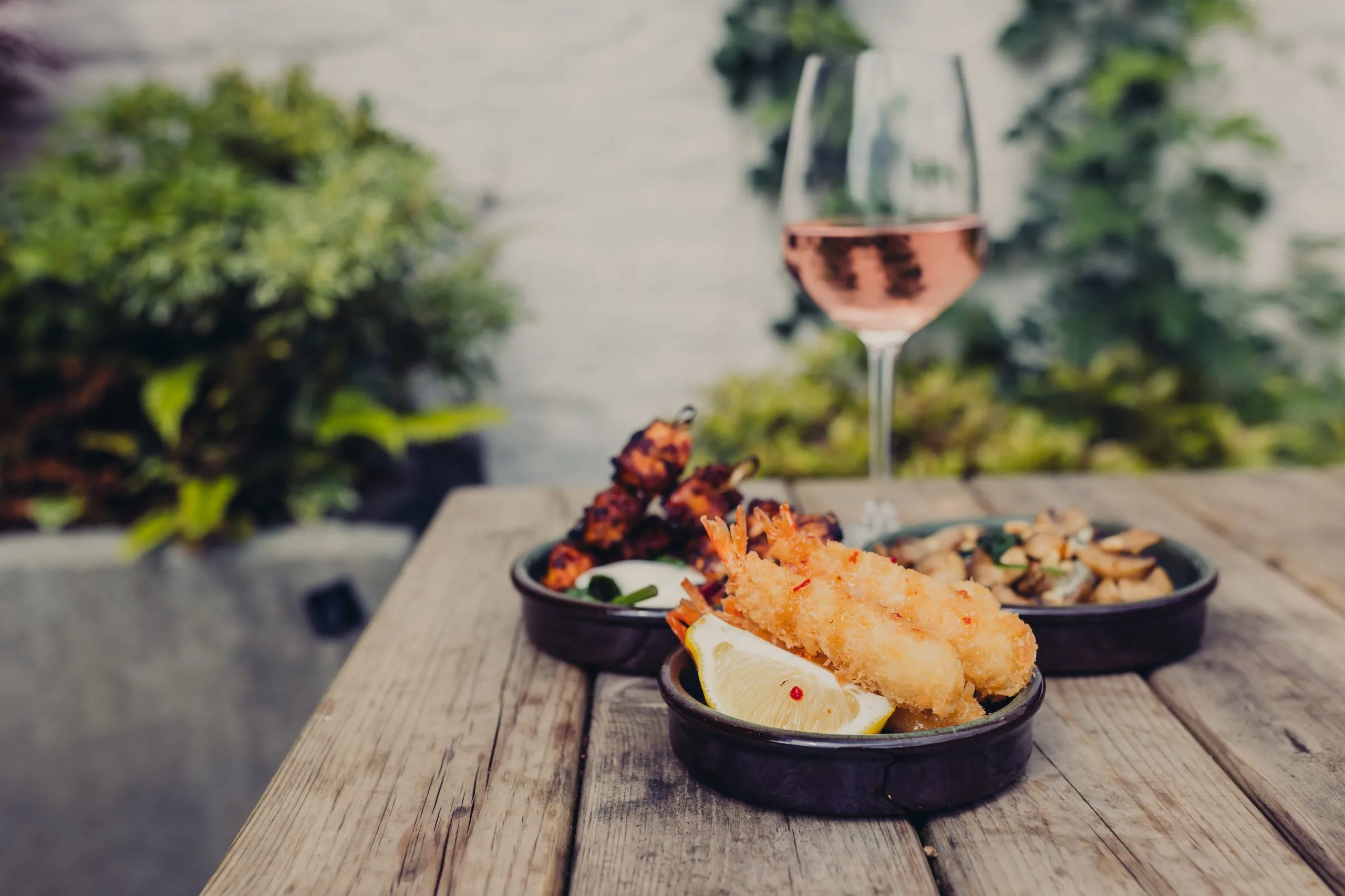 Table situated outside with several dishes and a wine glass