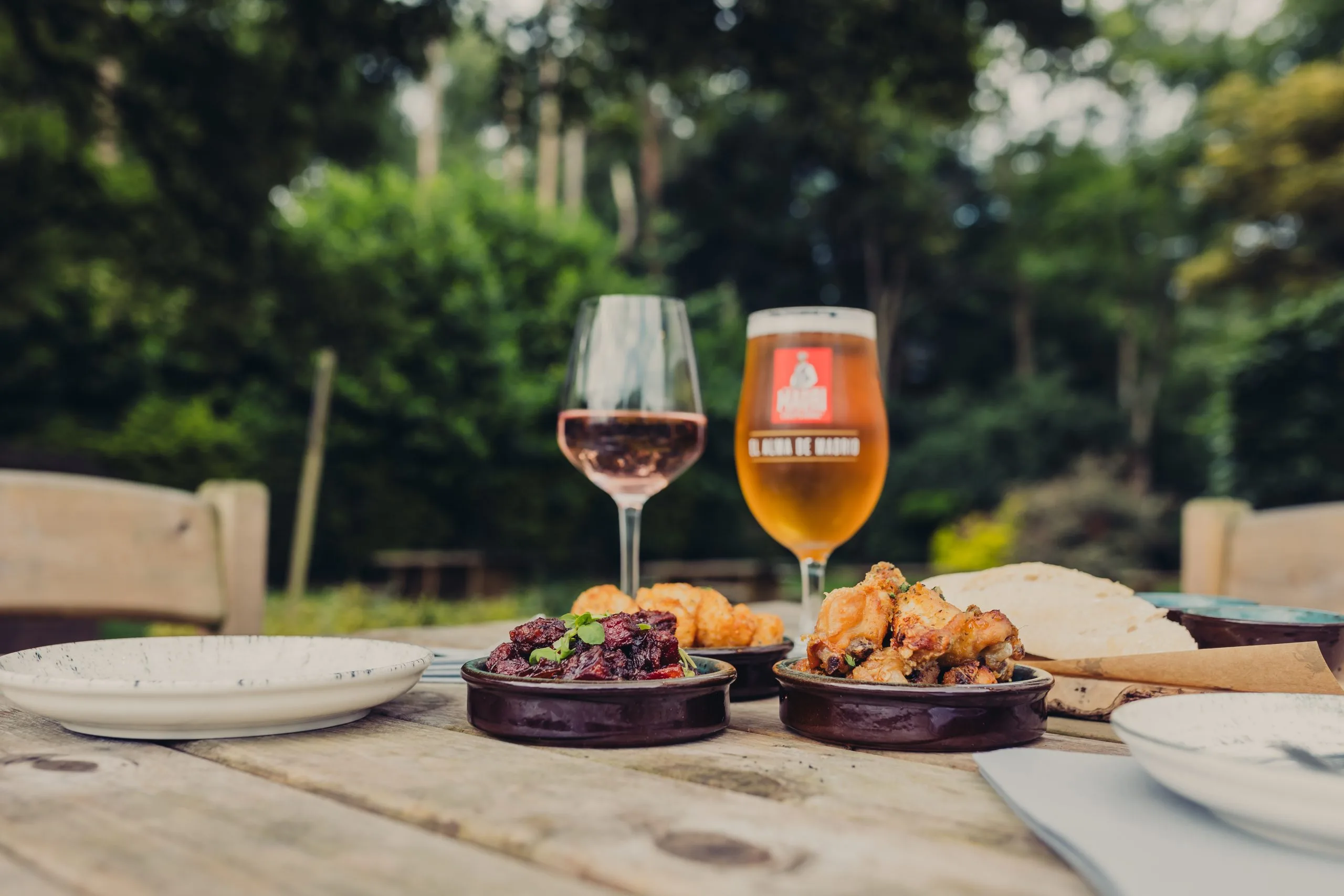 Table situated outside with two dishes and two wine glasses