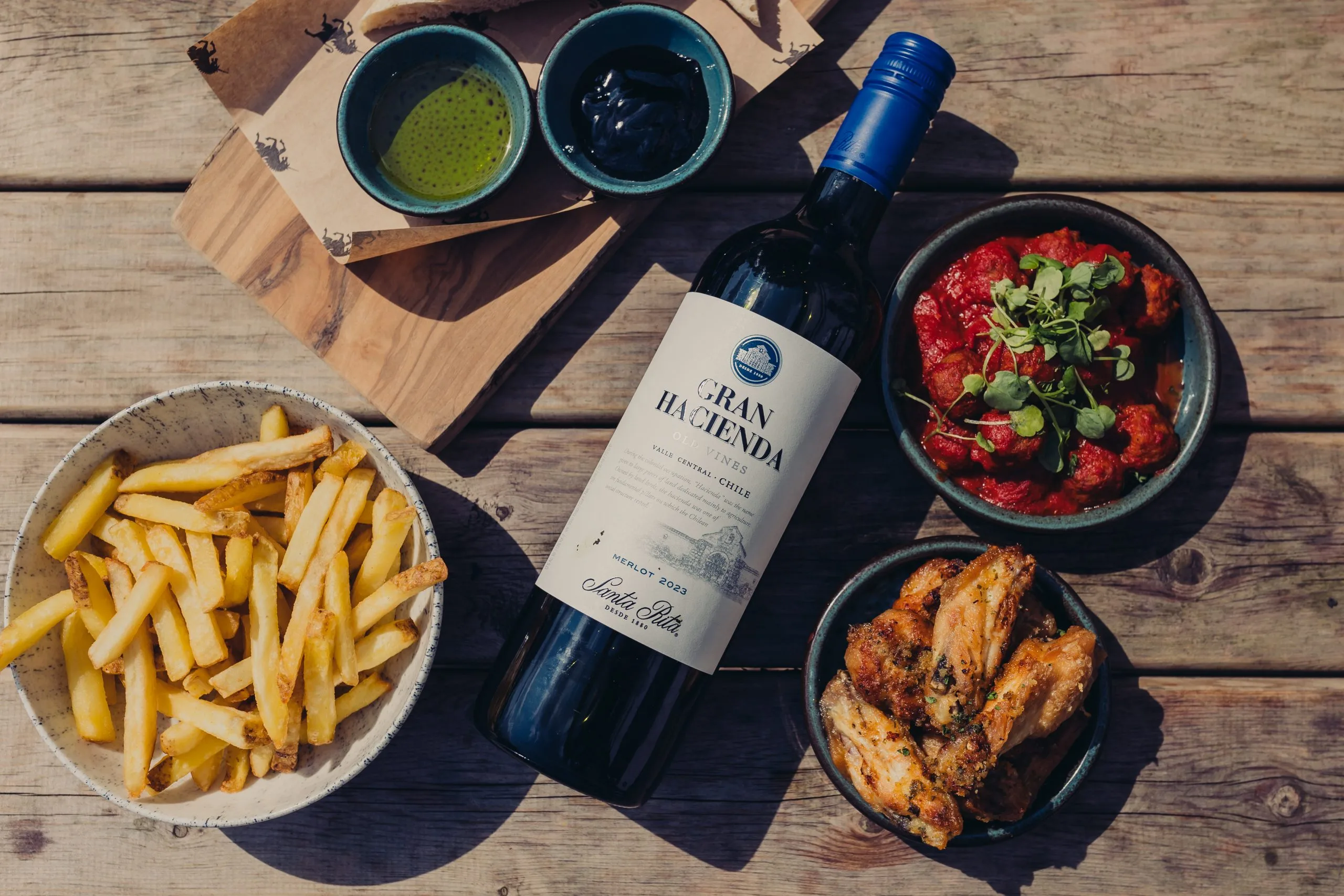 Various dishes on a table with a bottle of wine at the centre