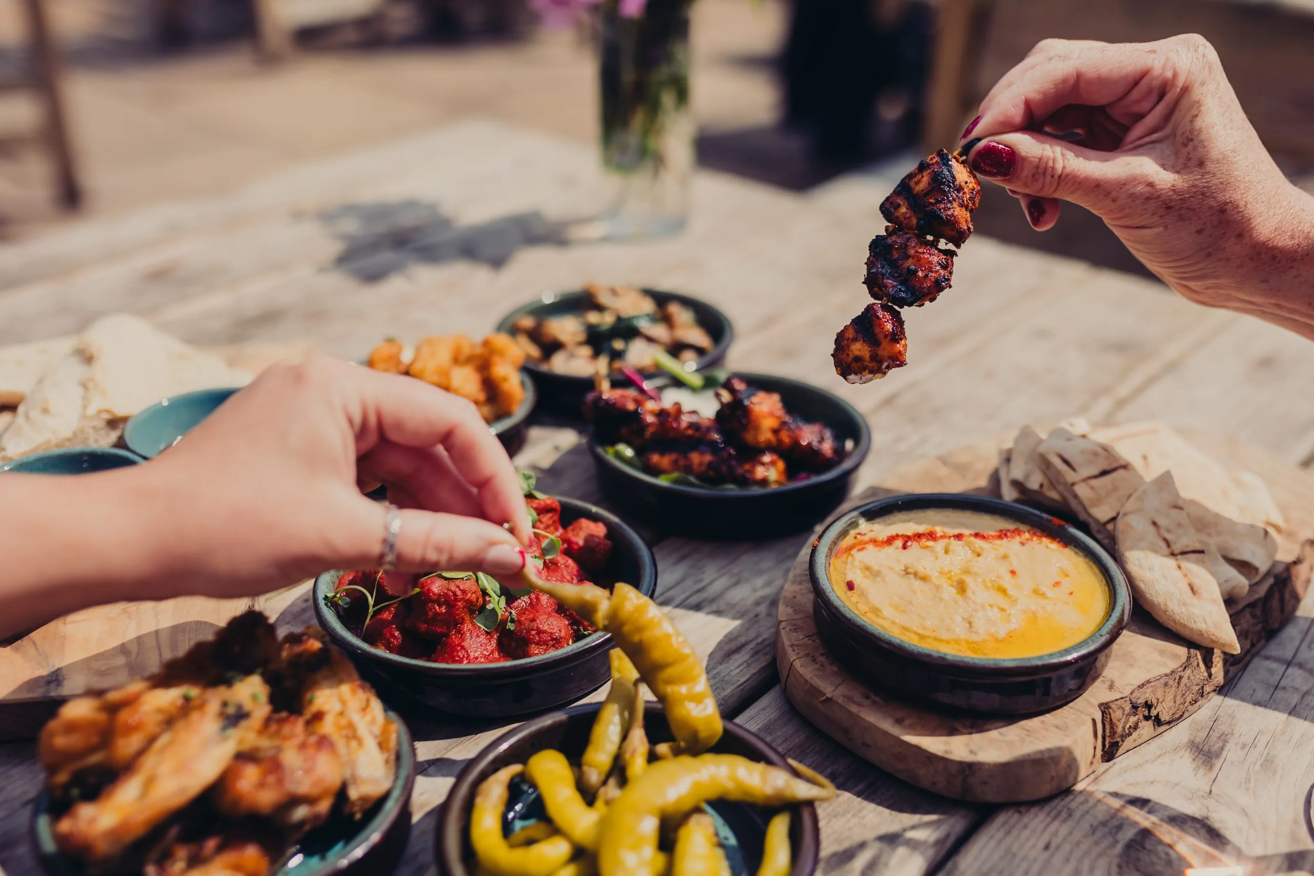 Various people holding items from the various dishes that are on the table